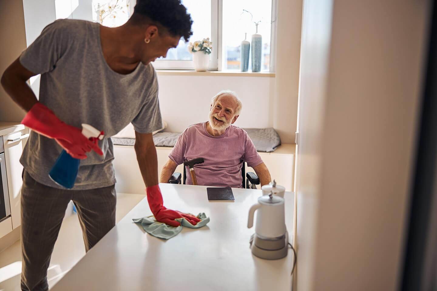 A man Cleaning Table and An Elderly Man sitting in a Wheelchear - ViaQuest Hospice